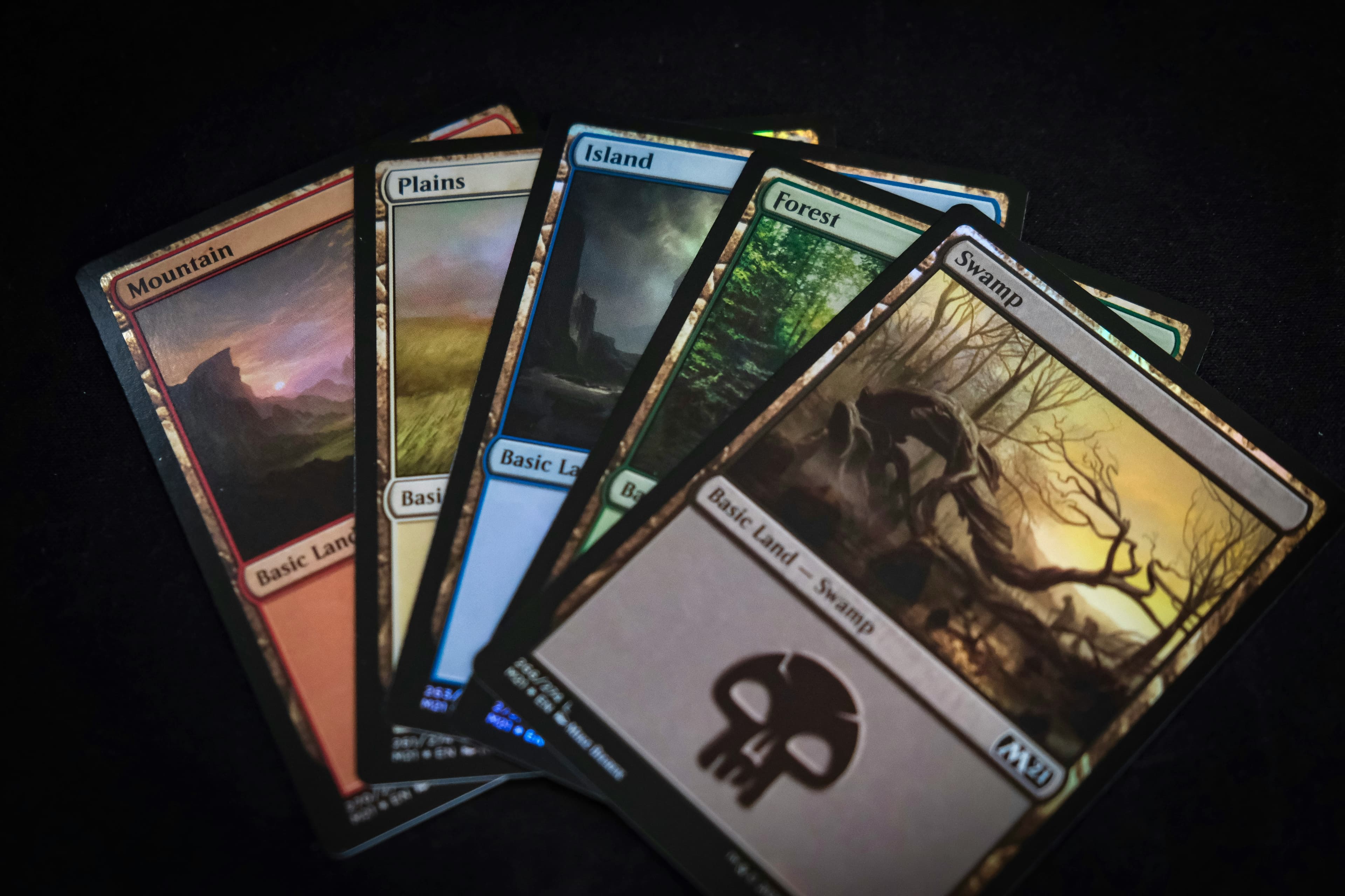 Pět basic land karet Magic: The Gathering na černém pozadí